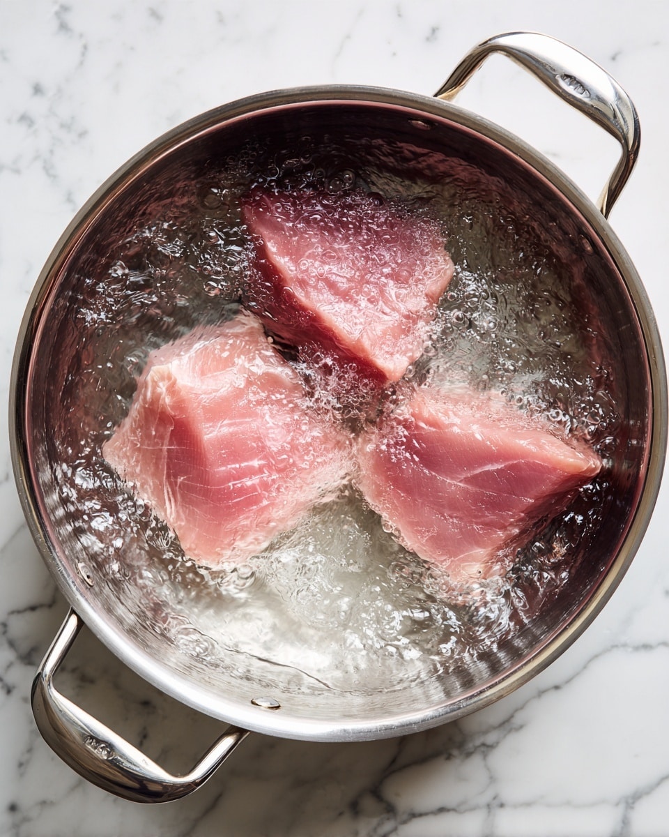 A close-up view of a large silver pot filled with boiling water on a white marbled surface, containing three thick, pale pink pieces of raw meat fully submerged. The water is bubbling vigorously around the meat, creating shiny reflections and steam rising from the pot. The pot has shiny handles on each side, and the edges show slight discoloration from use. photo taken with an iphone --ar 4:5 --v 7