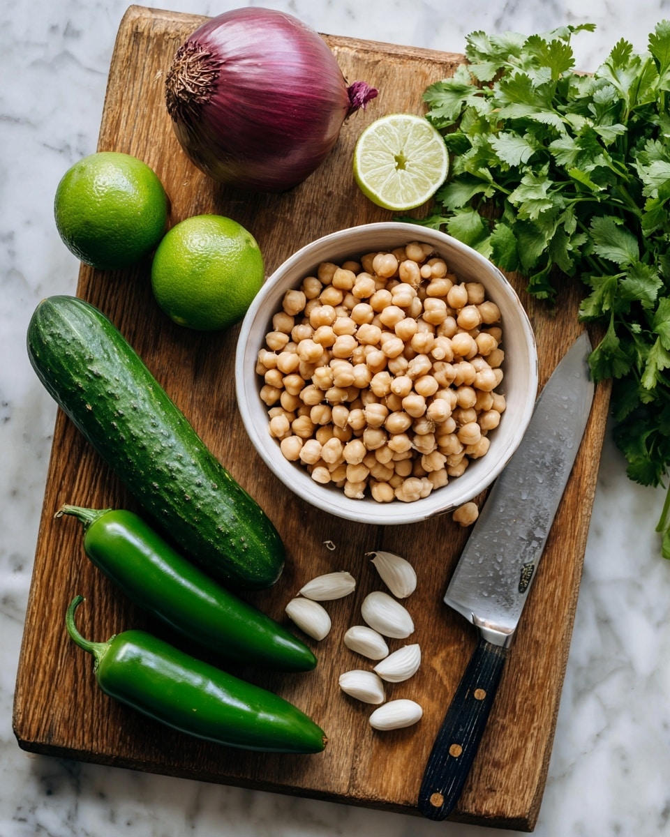 A wooden board sits on a white marbled surface, with a white bowl in the center filled with light brown chickpeas and white beans, the beans scattered slightly on top of the chickpeas. To the left of the bowl is a long dark green cucumber, two bright green limes stacked vertically, and three medium green jalapeño peppers lined up side by side. Several white garlic cloves are grouped near the limes and cucumber. Above the bowl is a large purple onion, and to the right of the bowl is a bunch of fresh green cilantro leaves next to a large knife with a shiny silver blade and a black handle. The wooden board has a natural warm tone. photo taken with an iphone --ar 4:5 --v 7