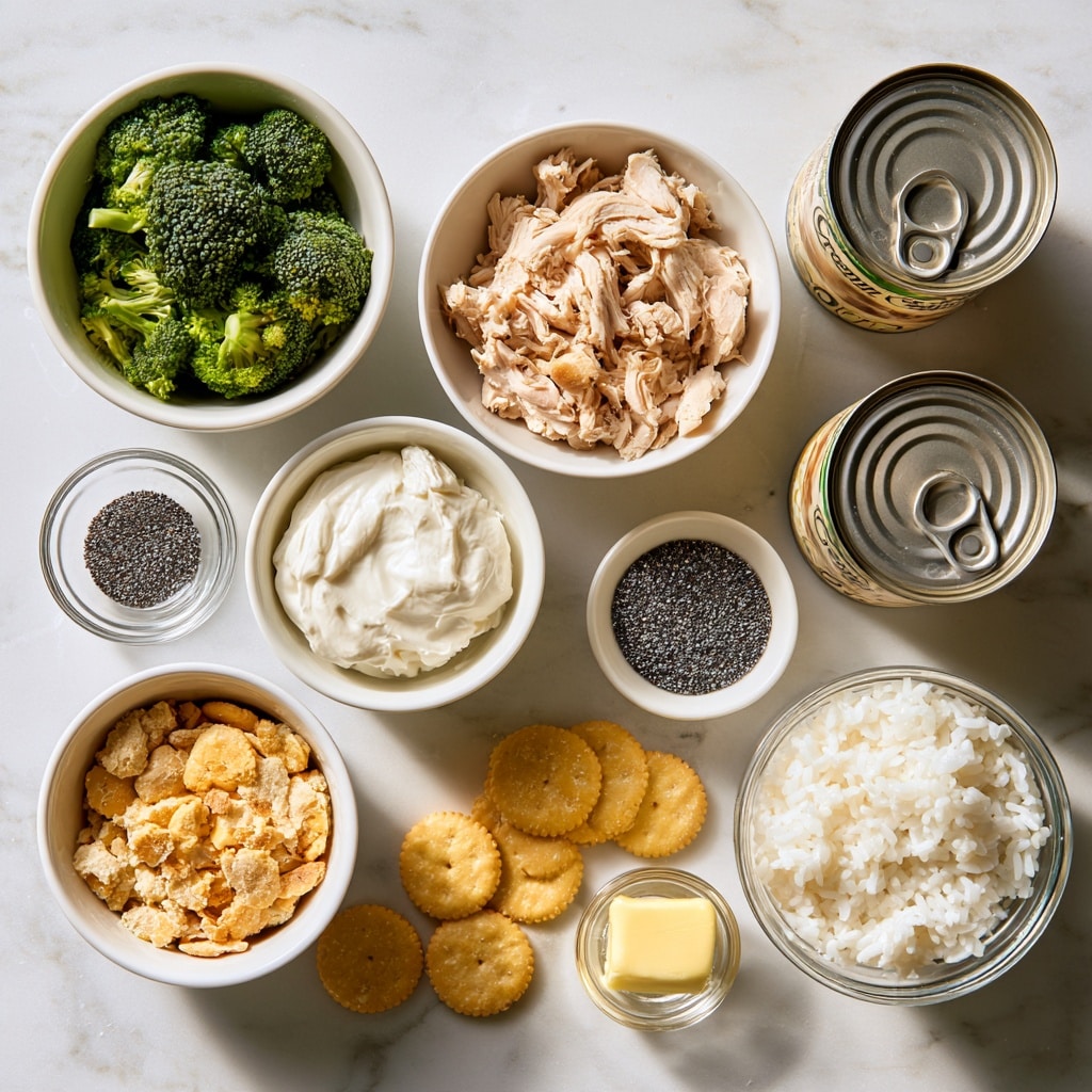 A clear glass bowl filled with creamy pasta salad that has three main layers: white bowtie pasta coated in a thick sauce, small pieces of light beige chicken mixed in, and bright green broccoli florets scattered throughout, all-speckled with small black pepper bits. A silver serving spoon rests inside the bowl on top of the pasta mixture, and the bowl is set on a white marbled tile surface. Photo taken with an iphone --ar 4:5 --v 7